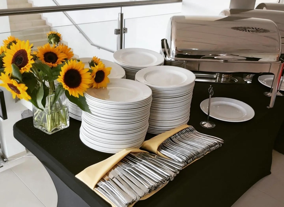 Przygotowany stół cateringowy z zastawą stołową i słonecznikami - catering Obieżyświat